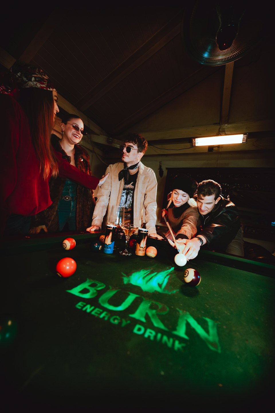 Five friends gather around a pool table for a game.