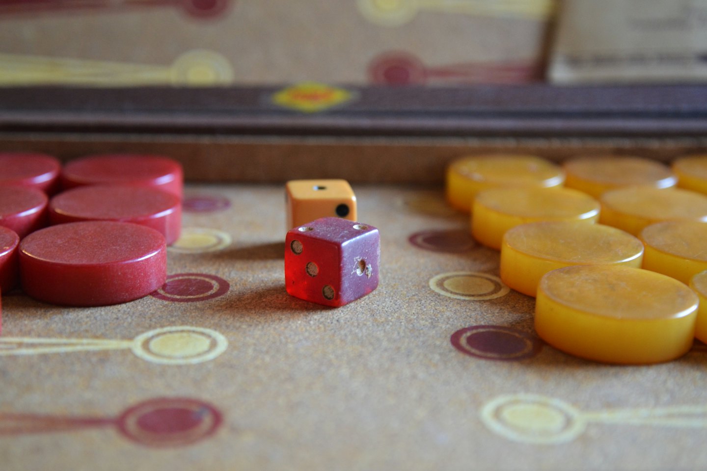 Red and amber backgammon pieces arranged on a wooden board.